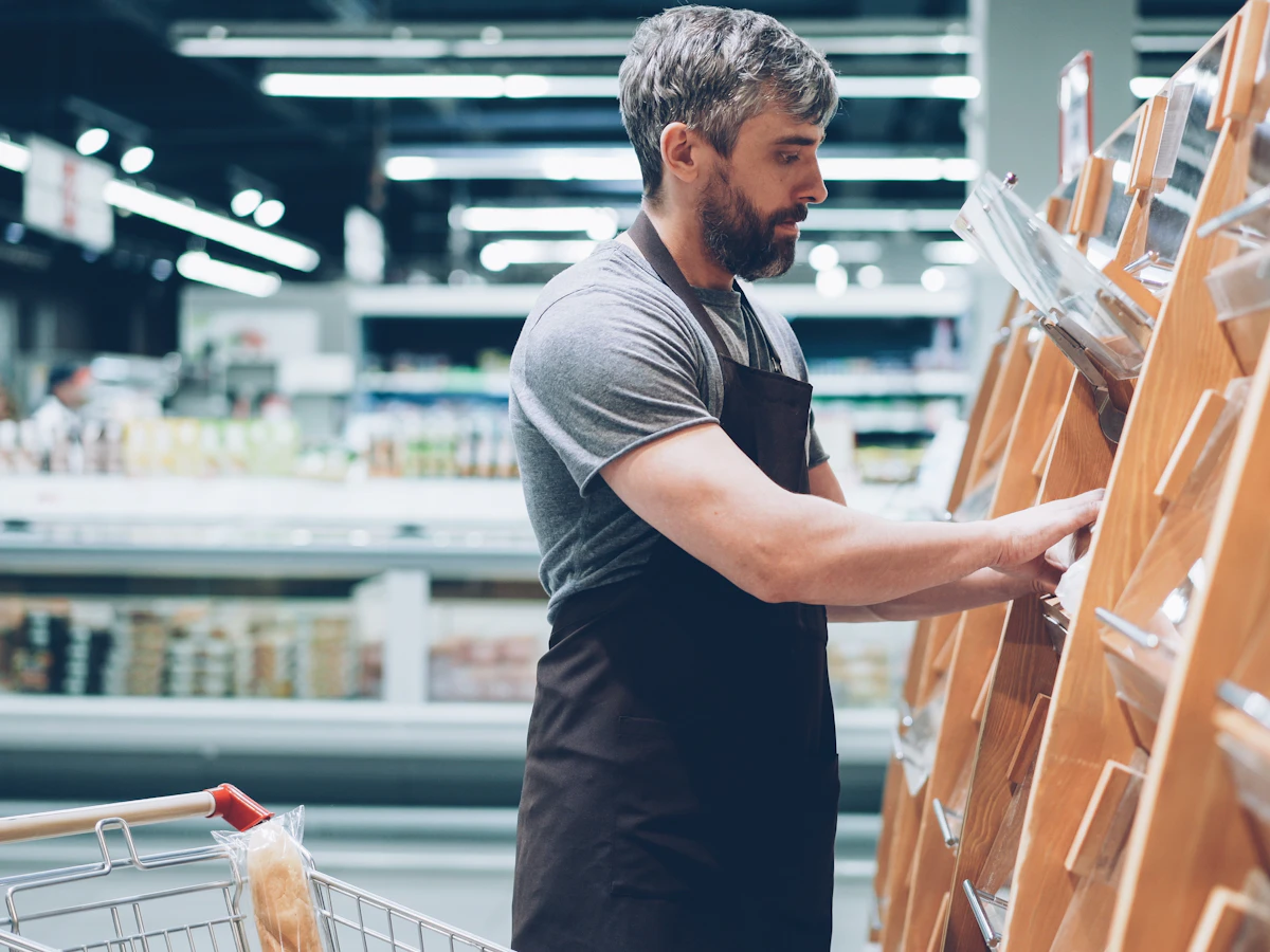 Un employé met du pain en rayon dans un magasin.